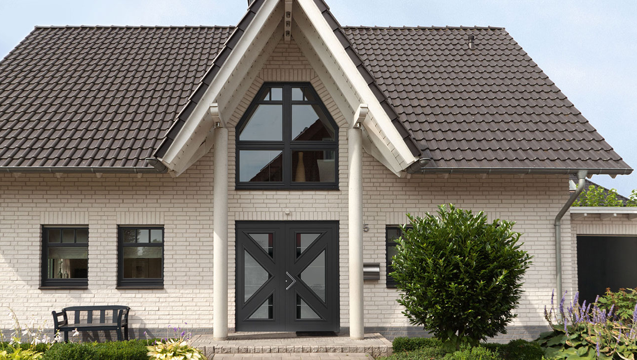 Ein weißes Backsteinhaus mit Stützsäulen am Eingang und einer Kompotherm Matisse Haustür