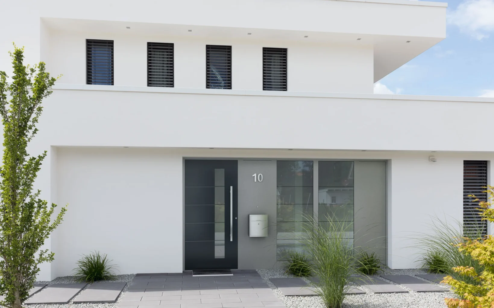 Modernes weißes Haus mit dunkler Haustür mit Glaseinsätzen