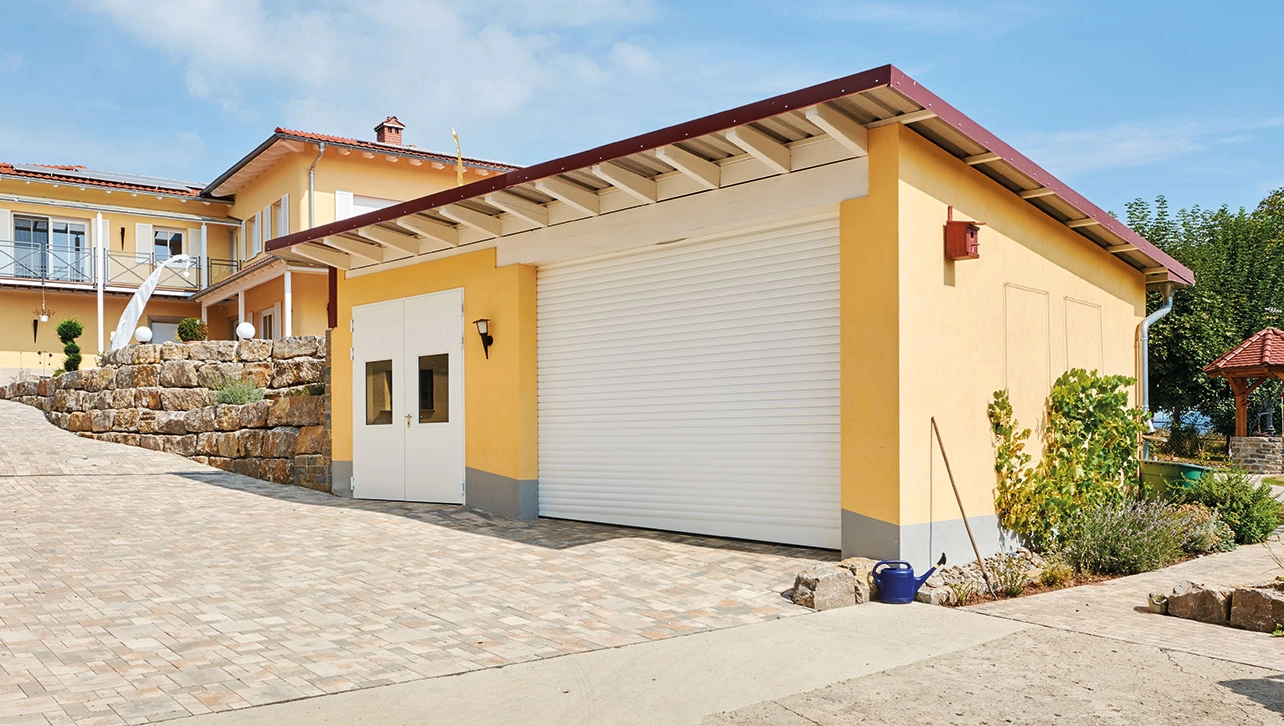 Weißes Rolltor an freistehender Garage mit Seitentoren