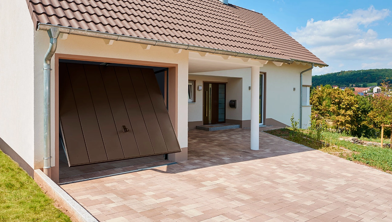 In Einfamilienhaus integrierte Garage mit einem braunen Schwingtor aus Metall