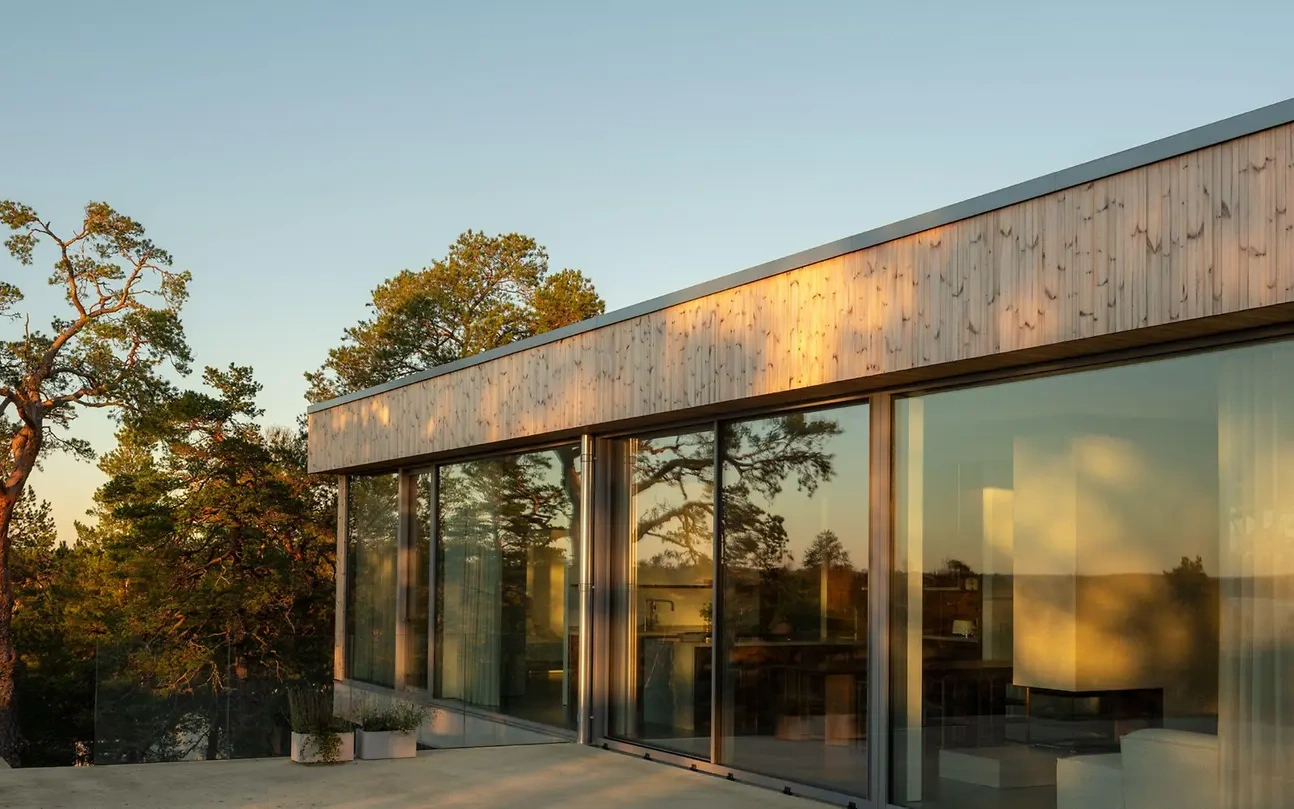 Sonnenbeschienene große Fensterfront eines modernen Hauses aus Holz