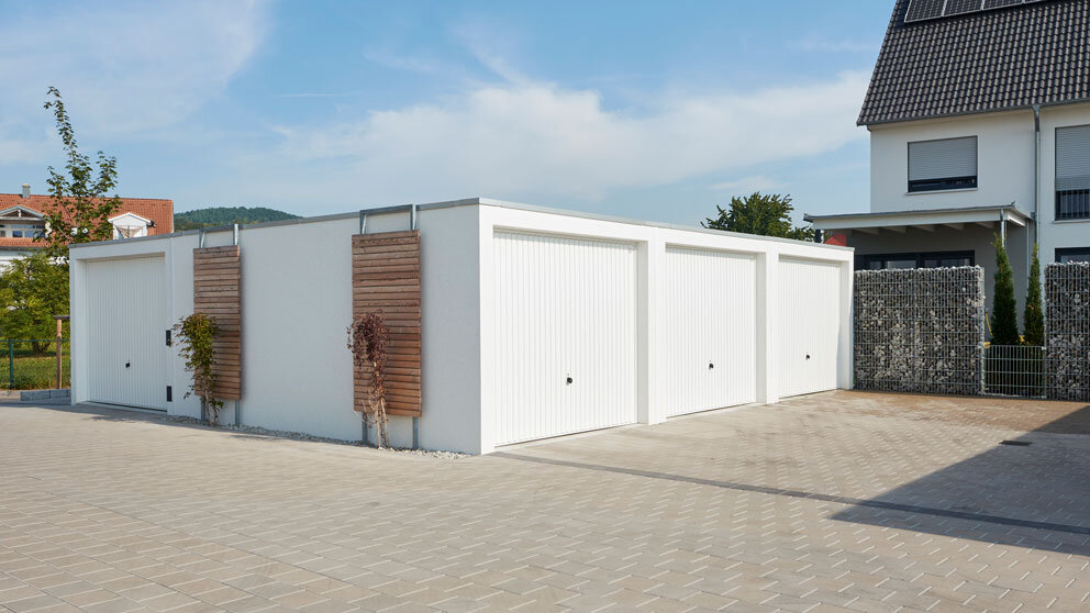 Dreifache Garage vor einem Hof mit weißen Schwingtoren