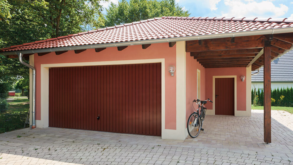 Große Garage mit Seiteneingang und passend eingefärbtem breiten Schwingtor