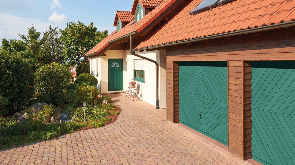 Haus mit grüner Haustür und doppelter Garage mit grün angestrichenen Schwingtoren aus Holz