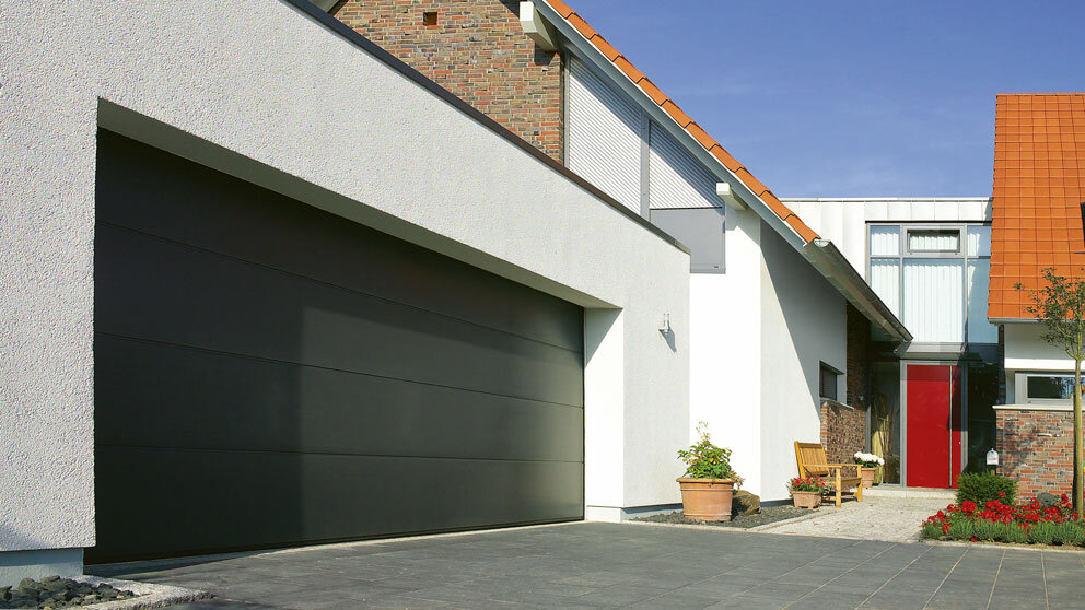 Breite Garage mit einem dunkelgrauen Steinau Sektionaltor