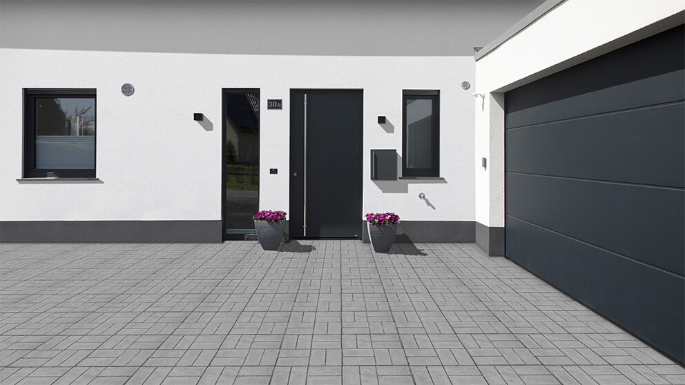 Eingangsbereich mit seitlich verbundener Garage mit dunkelgrauem Steinau Sektionaltor