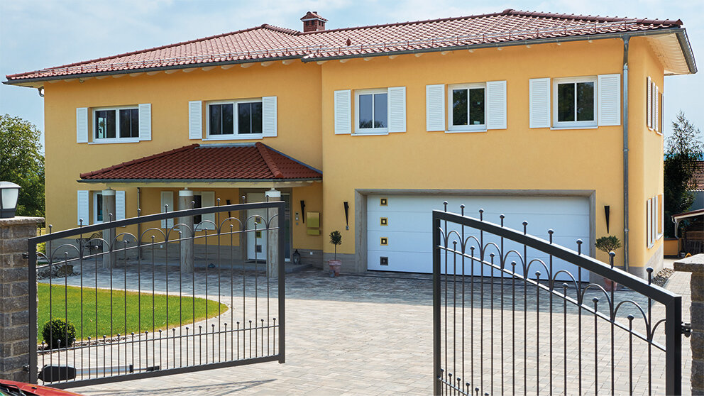Gelbes Doppelhaus mit integrierter Garage und weißem Sektionaltor mit Sichtfenstern