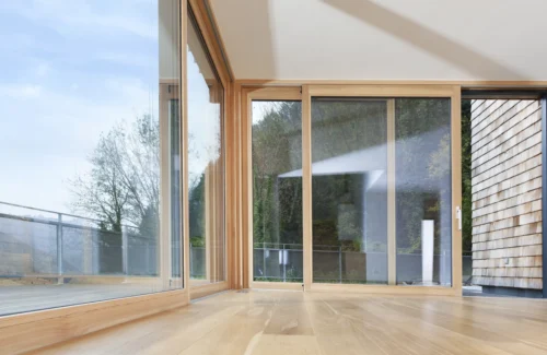 Holz-Aluminium Hebeschiebetüren als große Fensterfront vor einem Balkon.